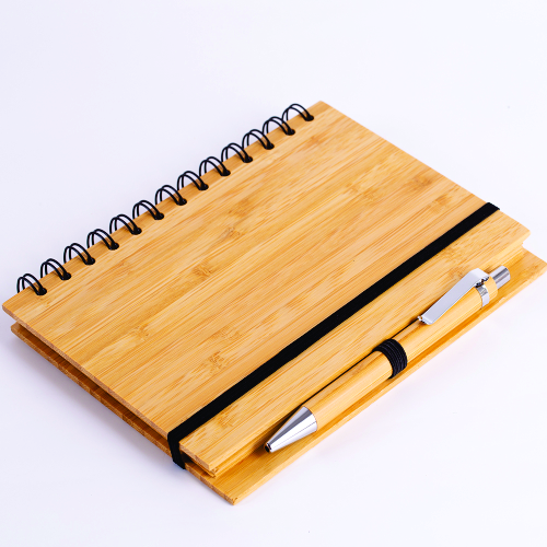 Novidade!!! Caderno em capa de bambu com elástico, suporte para caneta e com 70 folhas pautadas. 18 x 13,5 cm. Acompanha caneta de bambu com detalhes em plástico.